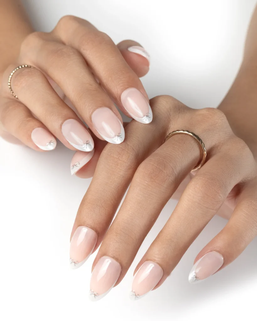 Soft nude press on nails with white French tips and minimal crystal detailing
