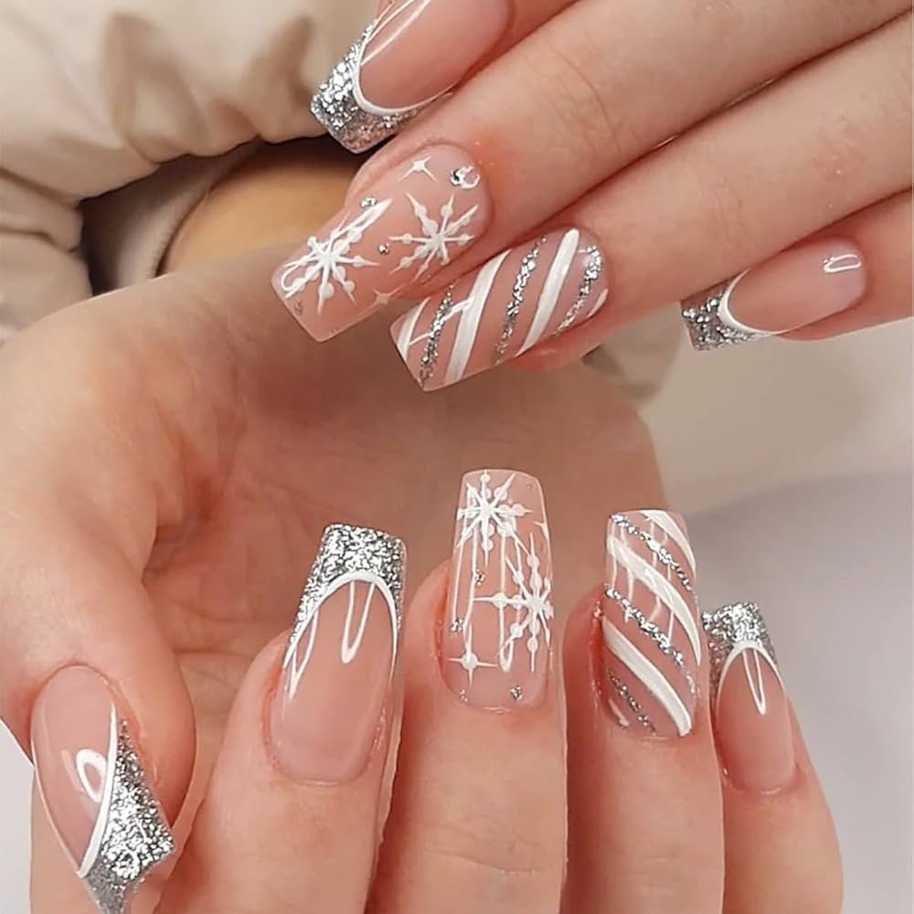 Nude press on nails with silver glitter tips, white snowflake nail art, and elegant stripe detailing