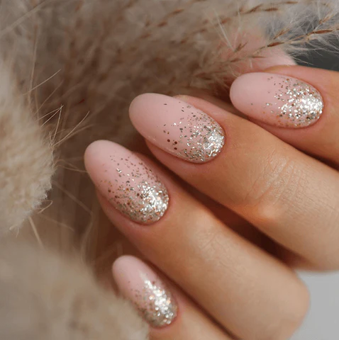 Soft pink press on nails with glitter ombre tips in an elegant almond shape